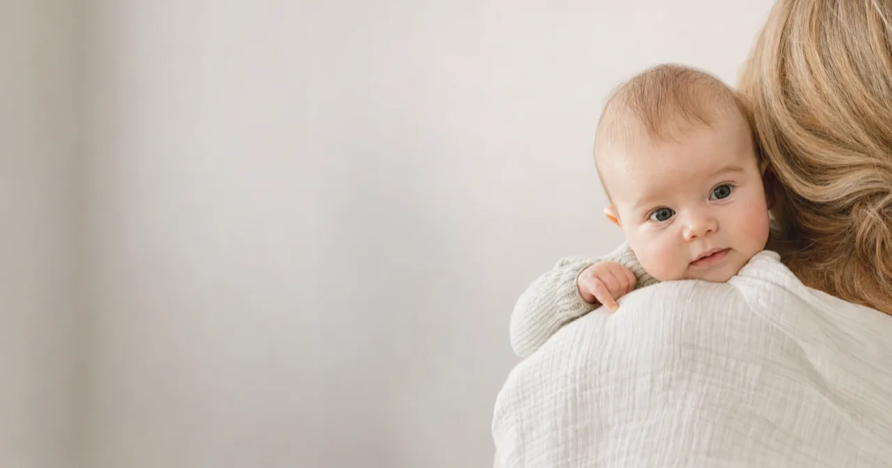 A baby with a cold held upright against a parent's shoulder